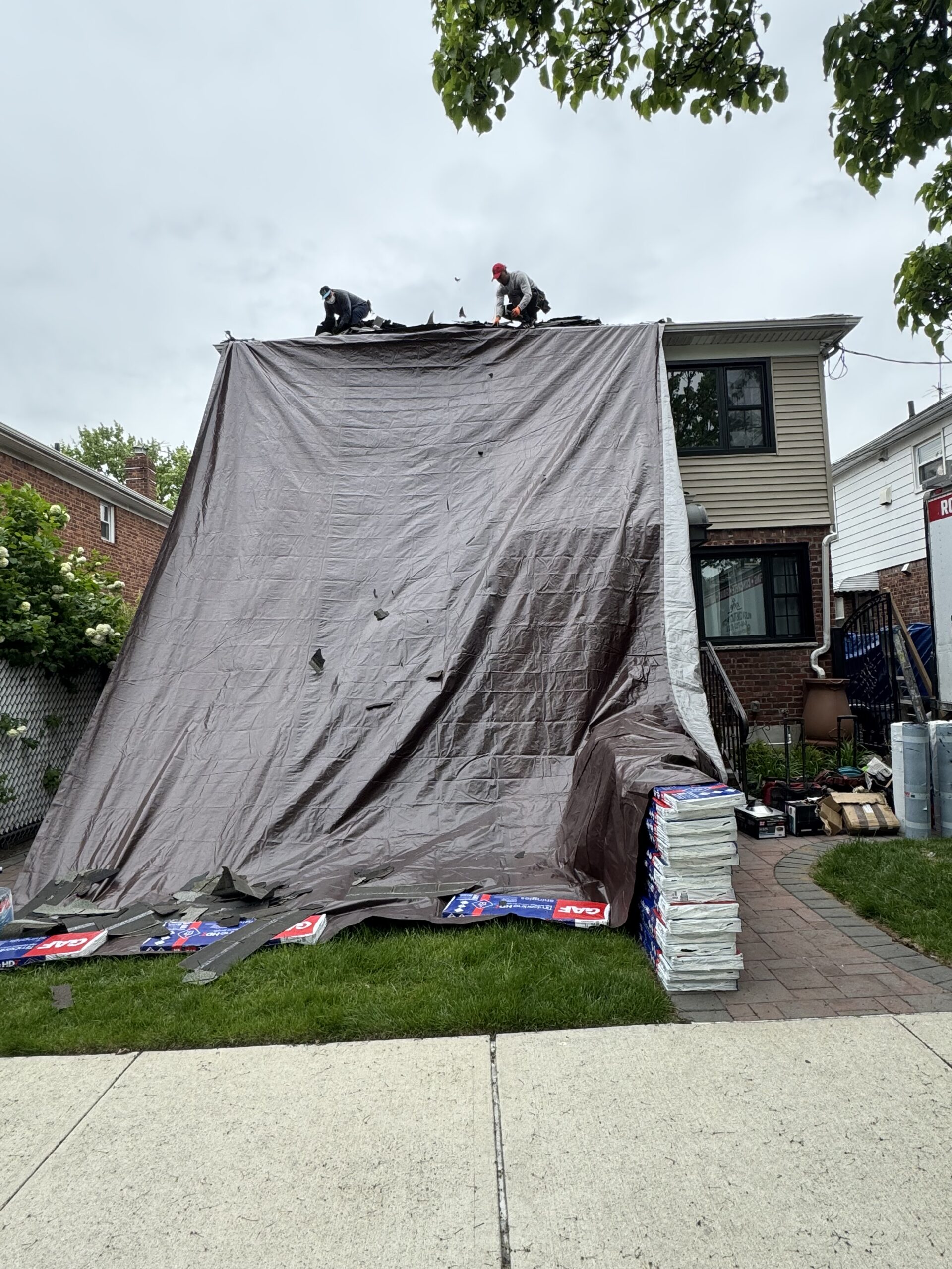 Roof replacement with protective tarp and shingle bundles